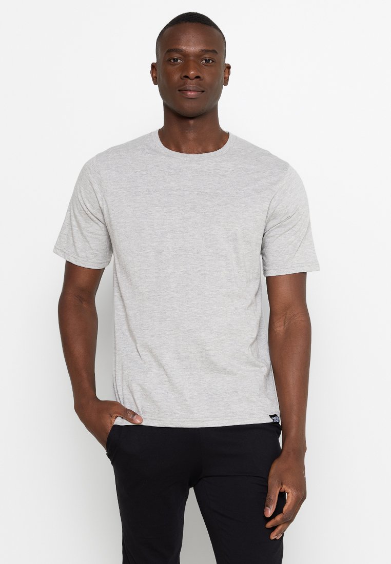 T-shirt gris à manches courtes en coton, avec un col rond et une coupe droite. Détail de logo notable sur le côté à l'ourlet.
