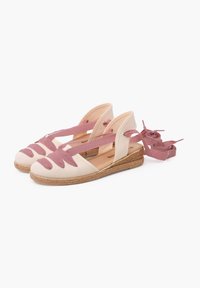 Sandales espadrilles en toile beige avec des accents en tissu rose. Présente une semelle plateforme et des lanières avec des détails floraux. Design à talon ouvert.