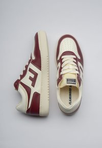 Bordowe i kremowe skórzane sneakersy z perforowanym noskiem, sznurowanym zapięciem, wyraźnym logo i teksturowaną gumową podeszwą.