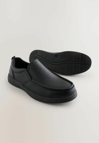 Black leather slip-on shoes with a smooth texture, accent stitching, and a rubber outsole featuring a tread pattern for grip.
