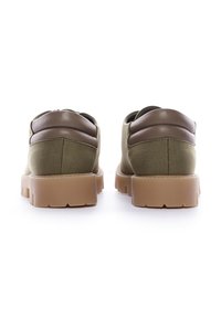 Scarpe di tela verdi con un colletto imbottito marrone e una suola in gomma spessa, che presentano una finitura testurizzata e un design elegante.