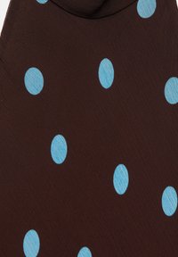 Tissu marron avec des pois bleu clair espacés régulièrement, montrant un gros plan du motif et de la texture.