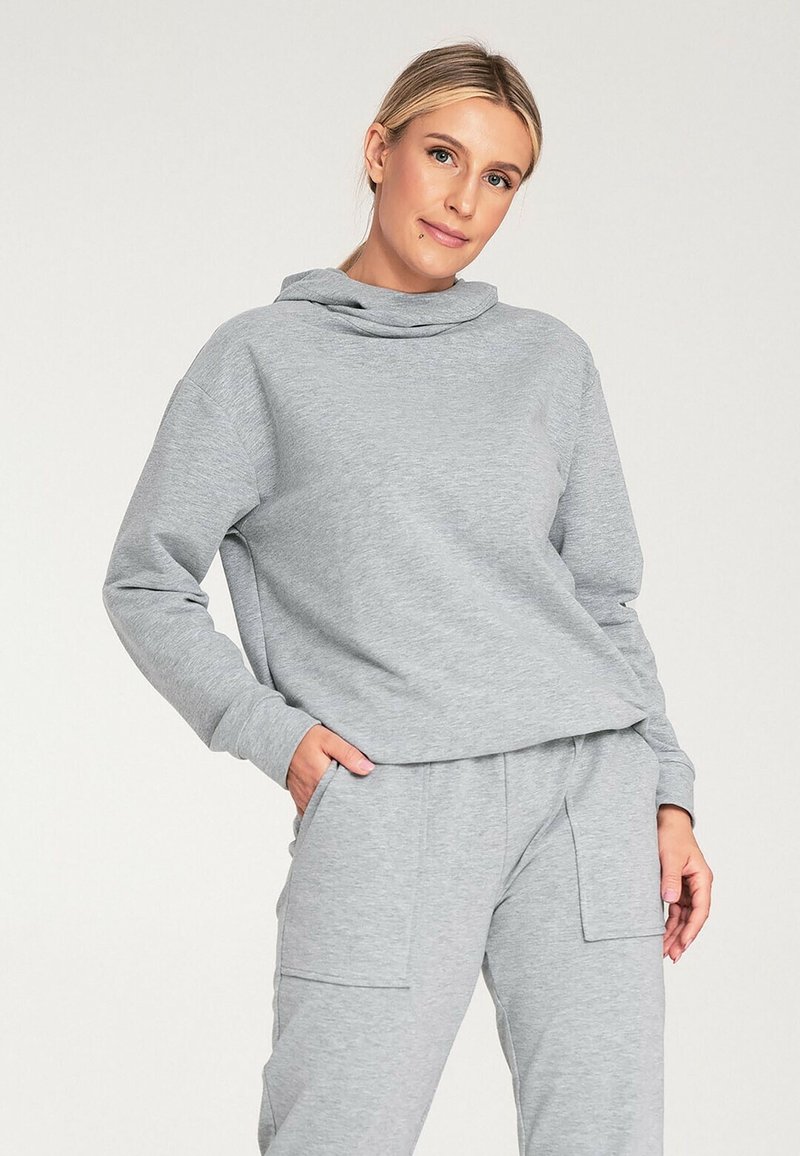 Szara bluza z kapturem, długimi rękawami i luźnym krojem. Wykonana z miękkiego materiału, w komplecie ze szarymi spodniami pasującymi, które mają kieszenie.