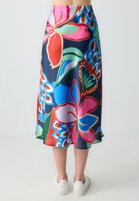 Een middelmatige rok met een marineblauwe achtergrond en levendige bloemmotieven in roze, rood, groen en blauw. Gladde stof en vloeiende ontwerp.