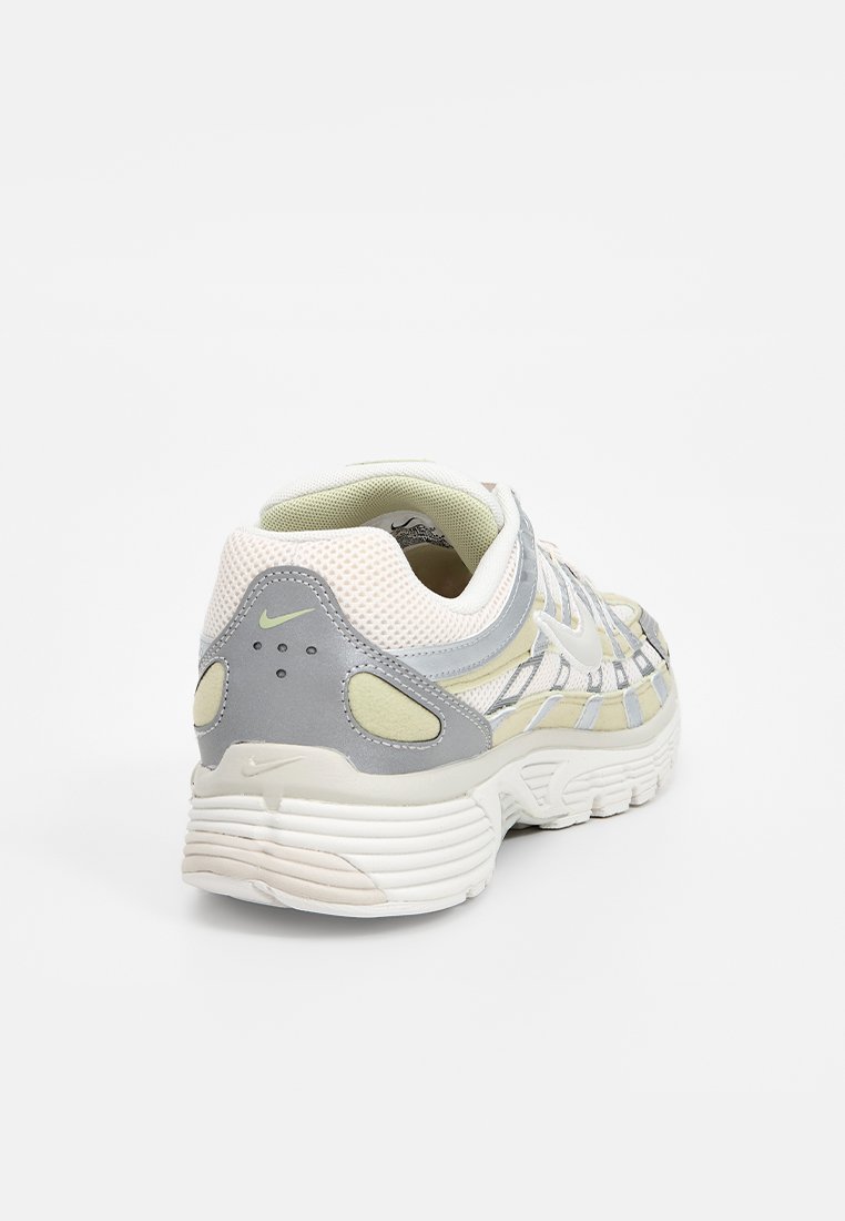 Baskets Nike avec une tige en mesh gris et jaune pâle, revêtement à motifs, semelle rembourrée et design de talon arrondi.
