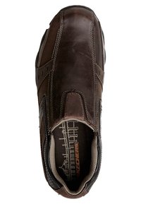 Chaussure en cuir marron à enfiler, présentant des accents sombres contrastants, une couture renforcée et une doublure intérieure texturée pour le confort.