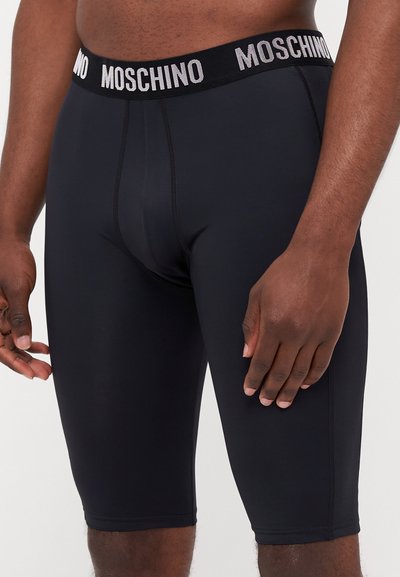 Boxer shorts noirs Moschino avec une large ceinture élastique arborant le nom de la marque en lettres blanches, design ajusté et texture lisse.