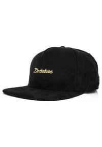 Gorra de ante negra con visera plana y corona redondeada. Presenta "Blackskies" bordado en cursiva dorada en la parte frontal.