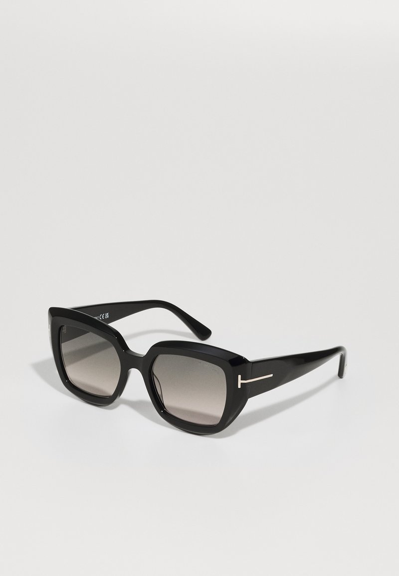 Occhiali da sole neri con una montatura rettangolare spessa, lenti in gradiente e un elegante accento argento sulle aste. Materiale plastico lucido.