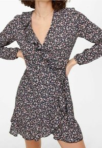 Czarna sukienka w kwiaty z falbanowym dekoltem w kształcie litery V, długimi rękawami i rozkloszowanym dołem. Charakteryzuje się małymi różowymi i białymi kwiatkami na ciemnym tle.
