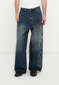 Traperice širokih nogavica u tamnoplavoj boji s izblijedjelim efektom, s detaljno izvezenim uzorkom na lijevoj strani i klasičnim dizajnom s pet džepova.