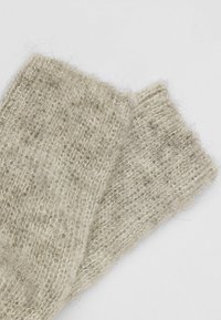Häkelte Handschuhe in Hellbeige, aus weicher, strukturierter Wolle gefertigt. Sie zeichnen sich durch eine lockere Webart aus und haben ein gemütliches, flauschiges Aussehen sowie ein natürliches Finish.
