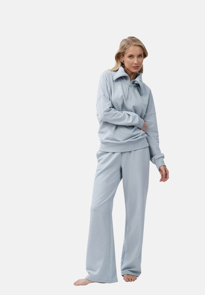 Lichtblauwe trainingsoutfit van zacht materiaal, met een ritssluiting bij de kraag, een ontspannen pasvorm, lange mouwen met geribbelde manchetten en een broek met wijde pijpen.