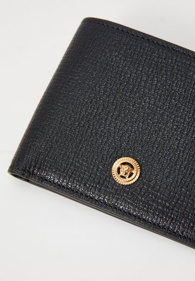 Black textured wallet featuring a gold lion emblem on a circular accent, showcasing a compact design with visible stitching details.