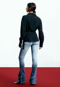 Bluză neagră cu mânecă lungă, cu talie subțiată și guler, asortată cu blugi deschiși la culoare, evazați, cu un efect ombre și detalii cu volan.