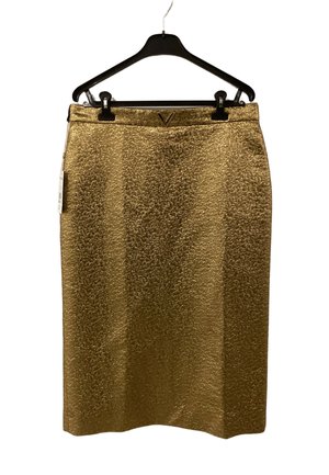 Jupe dorée texturée longueur genou suspendue sur un cintre noir avec des pinces, avec un petit embellissement métallique en forme de V à la taille.