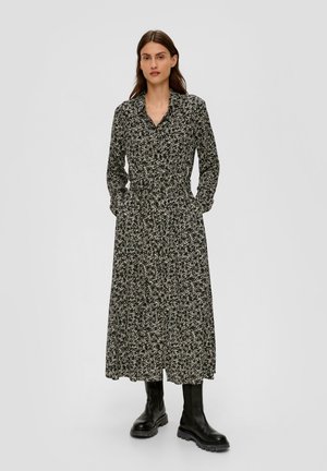 Zwart bloemenprint lange jurk met een kraag, knopen aan de voorkant en zijzakken. Gestyled met knielange zwarte laarzen.