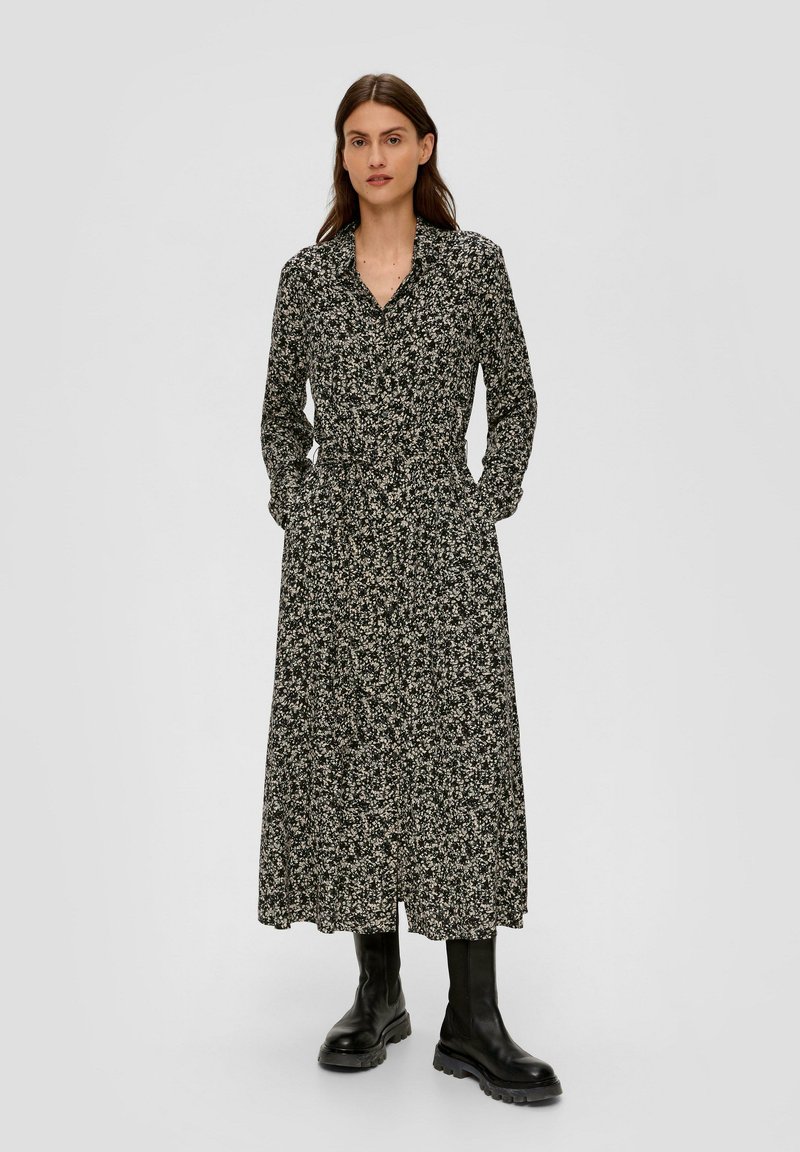 Zwart bloemenprint lange jurk met een kraag, knopen aan de voorkant en zijzakken. Gestyled met knielange zwarte laarzen.