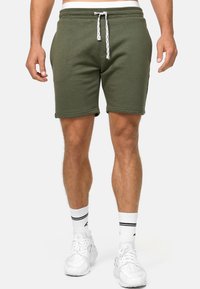 Olivegrüne Herren Shorts aus einem Baumwollmischgewebe. Mit einem Kordelzugbund, seitlichen Taschen und einem lässigen Schnitt mit umgeschlagenen Säumen.