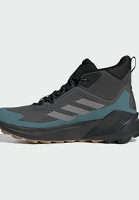 Czarno-szare buty sportowe z teksturowanym wierzchem, akcentami w kolorze teal i solidną podeszwą. Posiadają trzy szare paski po boku.