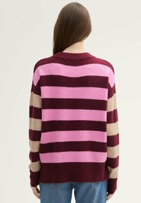 Strickpullover in burgunderrot, pink und beige mit horizontalen Streifen. Verfügt über einen gerippten Rundhalsausschnitt und lange Ärmel. Weiche Textur.