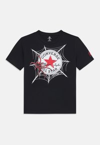 T-shirt noir avec un logo Converse rouge entouré d'une toile d'araignée, accompagné d'une illustration détaillée d'une araignée rouge près du logo.
