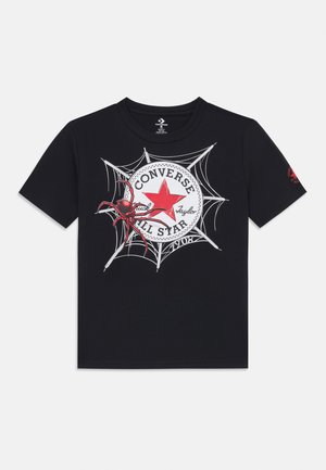 Tricou negru cu un logo roșu Converse închis într-o pânză de păianjen, având o ilustrație detaliată a unui păianjen roșu lângă logo.