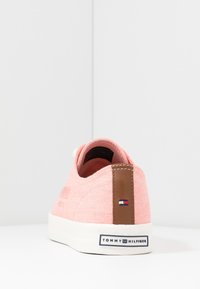 Pinkfarbener Leinenschuh mit braunem Akzent an der Ferse, weißer Gummisohle und Markenlogo auf der Rückseite. Schlichtes und schnörkelloses Design.