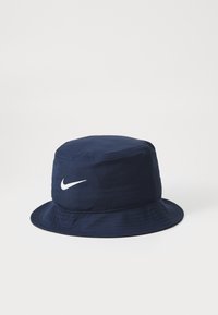 Tumesinine ämbri müts, mis on valmistatud kangast, ümar ja lai allapoole kaldu äär. Esiküljel on valge Nike logo.