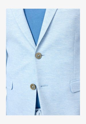 Světle modrý blazer s texturovanou látkou, jednoradový design, dva knoflíky a náprsní kapsa, vrstvený přes modrou košili.