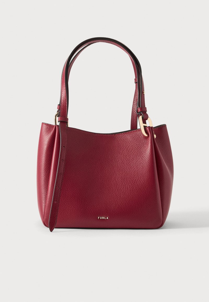 Κόκκινη τσάντα χειρός Furla από δέρμα με υφή, με δύο κοντά χερούλια και μεταλλικά στοιχεία σε χρυσό χρώμα σε απλό φόντο.