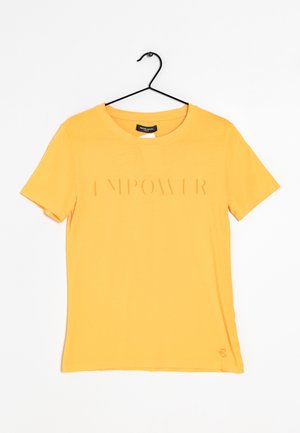 Gul T-shirt med korte ærmer på en sort bøjle med præget tekst "EMPOWER" på tværs af brystet og et lille broderet logo nær kanten.