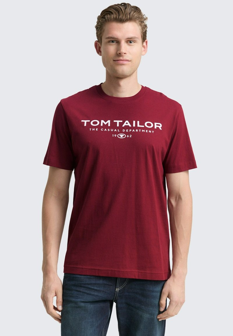 Rode katoenen T-shirt met korte mouwen en witte opdruk met de tekst "TOM TAILOR THE CASUAL DEPARTMENT 1962." Standaard pasvorm, ronde hals.