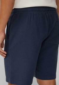 Marineblaue Shorts aus strukturiertem Stoff, mit einem elastischen Bund und einer Gesäßtasche für zusätzliche Funktionalität.