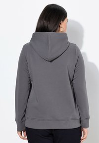 Sudadera con capucha gris de textura suave y puños acanalados. Presenta un bolsillo tipo canguro y un diseño de corte relajado.