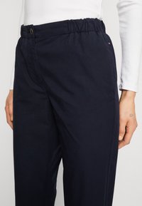 Námořnicky modré kalhoty s elastickým pasem, zapínáním na knoflík a bočními kapsami. Měkká textura a pohodlný střih pro maximální komfort.