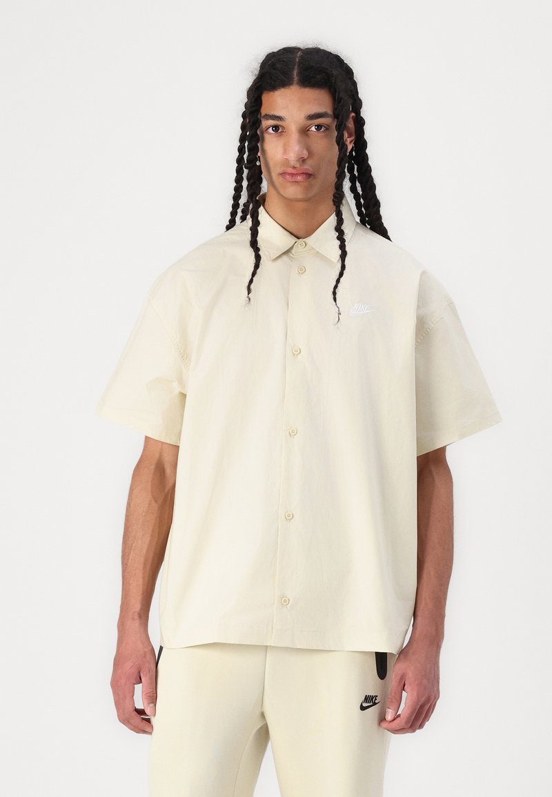 Κοντομάνικη, πουκαμίσα με κουμπιά σε παλ κίτρινο, κατασκευασμένη από ελαφρύ ύφασμα, με μικρό άσπρο λογότυπο στο στήθος και άνετη εφαρμογή.