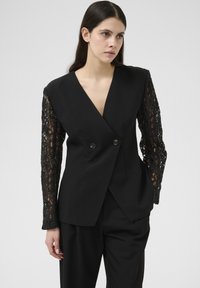 Sort blazer med dobbel-breasted design, blonde lange ærmer og glat stof. Har frontknapper og en skræddersyet pasform.