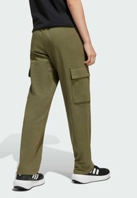 Pantaloni cargo verde oliva realizzati in tessuto morbido, con tasche laterali, una vestibilità comoda e un design a gamba affusolata. Abbinati a sneakers nere.