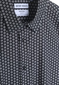 Camicia nera a maniche lunghe con design slim fit, caratterizzata da un motivo geometrico bianco, trama di tessuto contrastante e colletto standard.