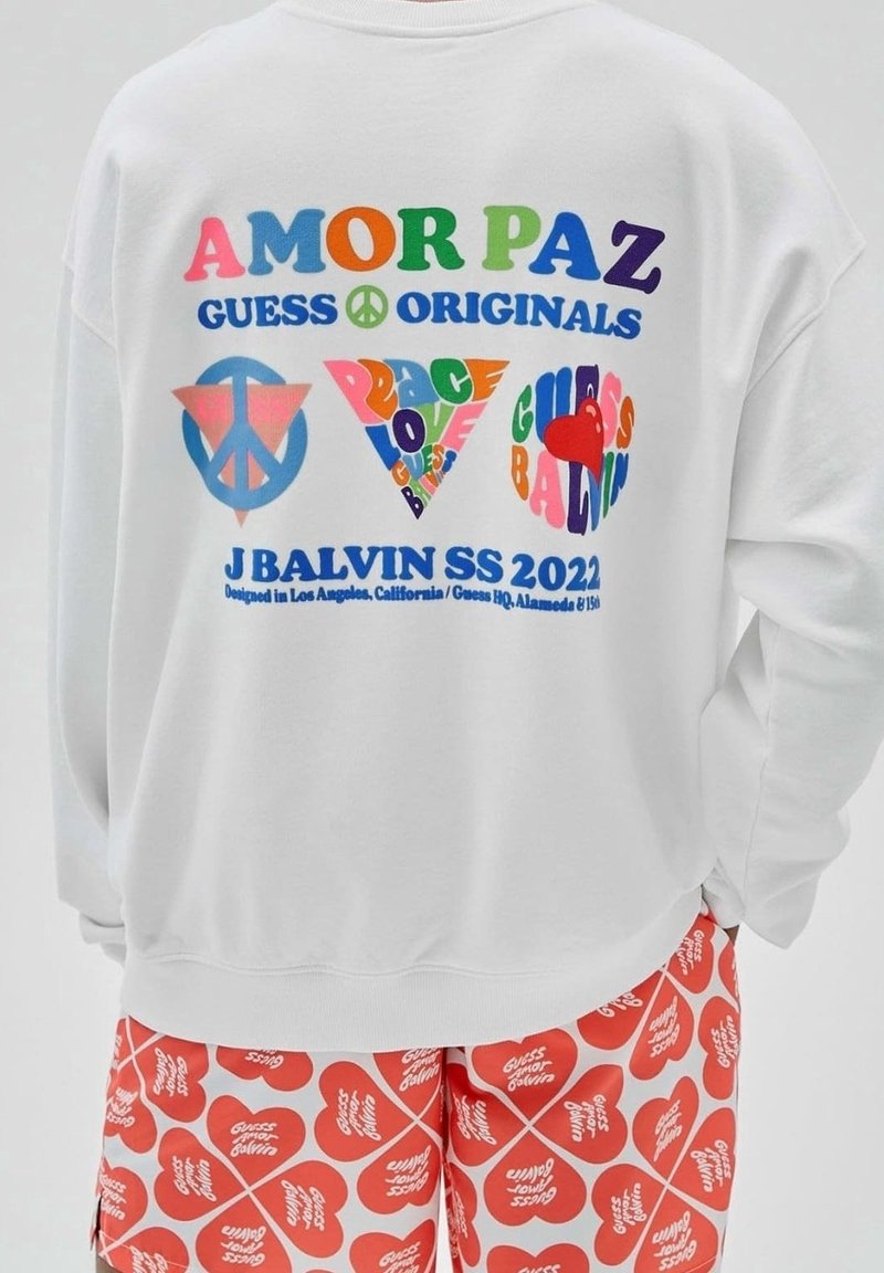 Witte sweatshirt met meerkleurige tekst en vredessymbolen op de achterkant. Heeft gedurfde graphic ontwerpen, een oversized pasvorm en een ronde halslijn.