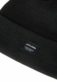 Zwart gebreide muts met geribbelde textuur en opgerolde rand, voorzien van een wit merkembleem aan de voorkant.