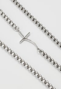 Sølvmetal kædetrøje med afrundede led og et centralt korsvedhæng med en glat overflade og poleret finish.
