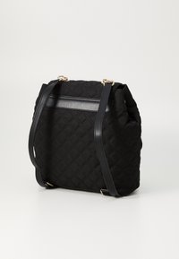 Schwarze gesteppte Stofftasche mit glatten Lederelementen, ausgestattet mit einem großen Hauptfach, verstellbaren Schultergurten und goldfarbener Hardware.