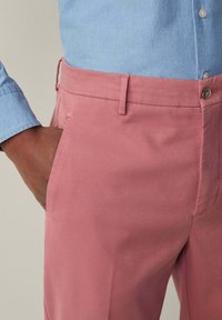 Rosa Baumwollhosen mit Slim-Fit, ausgestattet mit Seitentaschen, Gürtelschlaufen und einem einzelnen Knopfverschluss an der Taille.