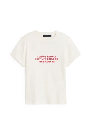 T-shirt blanc en coton avec manches courtes et col rond. Texte imprimé en rouge : « JE NE SAVAIS PAS QU'UNE VIE FACILE POUVAIT ÊTRE AUSSI DIFFICILE. »