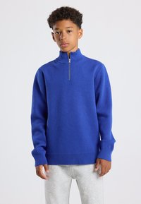 Koninklijk blauwe gebreide pullover met een hoge ritskraag, lange mouwen en geribde manchetten en zoom. Zachte textuur met een casual pasvorm.