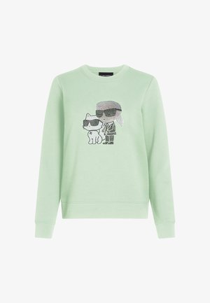 Müntroheline kapuutsiga paita, millel on graafika, kus on kujutatud tegelaskuju ja kass, mõlemad kandmas päikeseprille, kaunistatud läikivate detailidega.