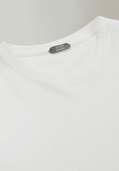 Weißes Baumwoll-T-Shirt mit rundem Ausschnitt und sichtbaren Nahtdetails. Das Etikett trägt die Aufschrift "ZANONE ice cotton". Glatte Textur.
