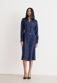 Abito blu navy con cintura, colletto, maniche lunghe e motivo testurizzato con forme circolari in diverse sfumature. Finitura di tessuto liscia.